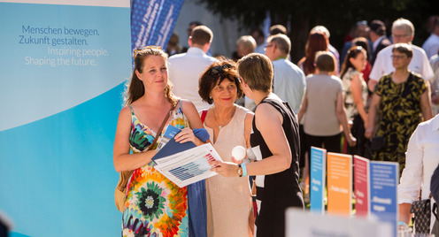 Daniela Schmidt, Projektmanagerin der Bertelsmann Stiftung, unterhält sich am Stand der Stiftung und des Liz Mohn Centers auf dem Bürgerfest des Bundespräsidenten mit zwei Besucherinnen.