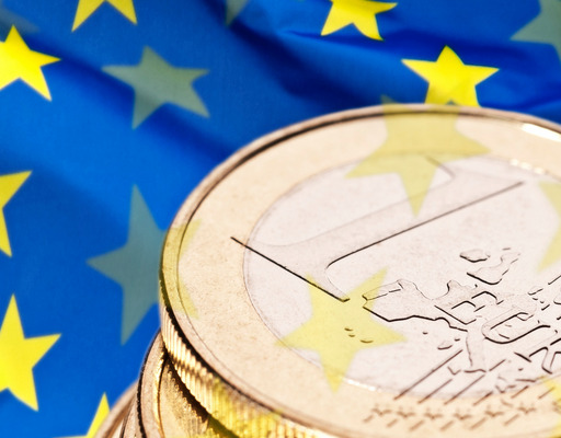 A stack of 1 euro coins against the backdrop of a European flag.