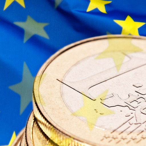 A stack of 1 euro coins against the backdrop of a European flag.