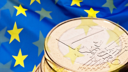 A stack of 1 euro coins against the backdrop of a European flag.