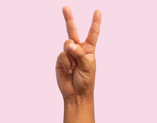 A person does the "peace" sign with her or his hand. Index and middle finger are forming a letter "V".