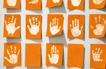 Kinderhände auf orangefarbenen Papierkarten