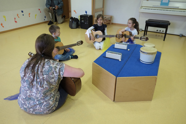 Kinder sitzen auf dem Fußboden und spielen Gitarre