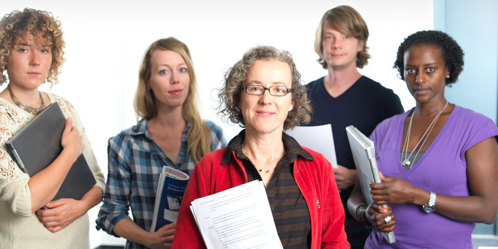 Fünf Personen stehen mit Heftern in der Hand der Kamera zugewandt.