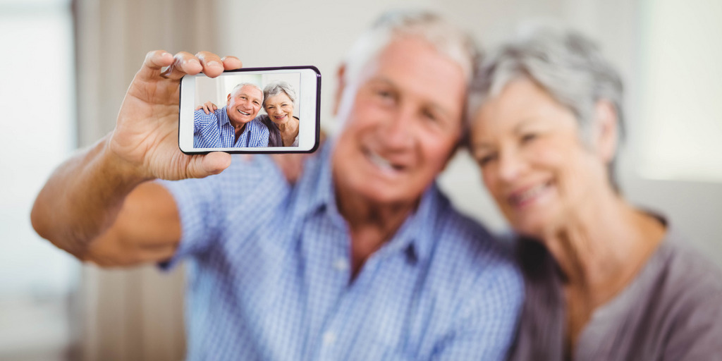 Ein älteres Paar macht mit einem Smartphone ein Bild von sich.