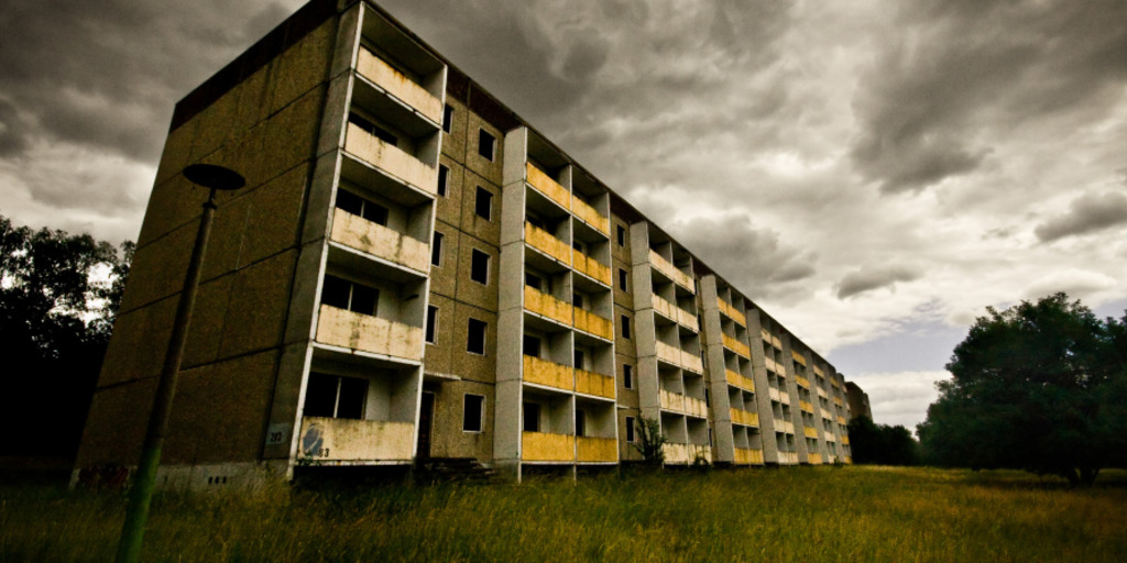 Dunkle Wolken über verfallenen Plattenbauten in Brandenburg