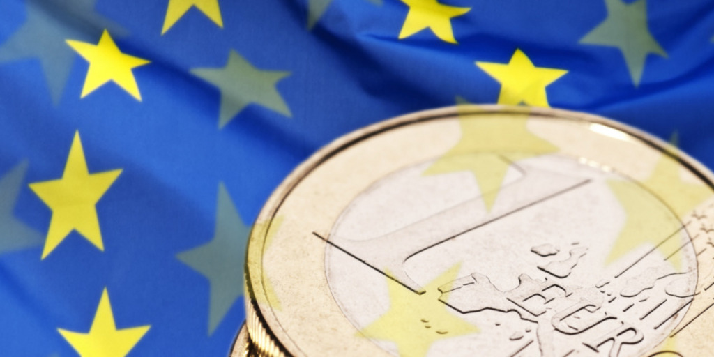 Teilansicht einer 1-Euro-Münze mit Europa-Flagge im Hintergrund. 
