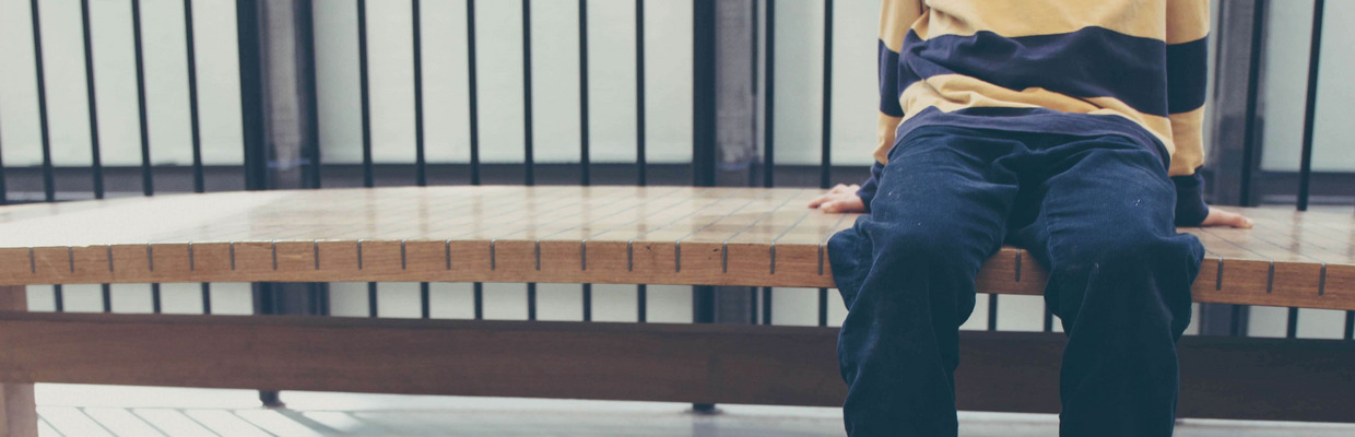 Ein Kind sitzt auf einer Bank