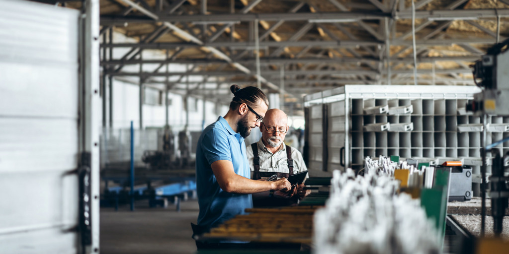 Junger Manager mit Mitarbeiter in einer Produktionshalle