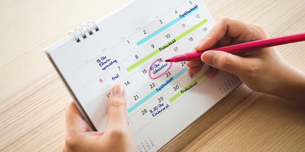 Eine Frau markiert mit einem Stift in ihrem Kalender ihren Termin beim Jobcenter.