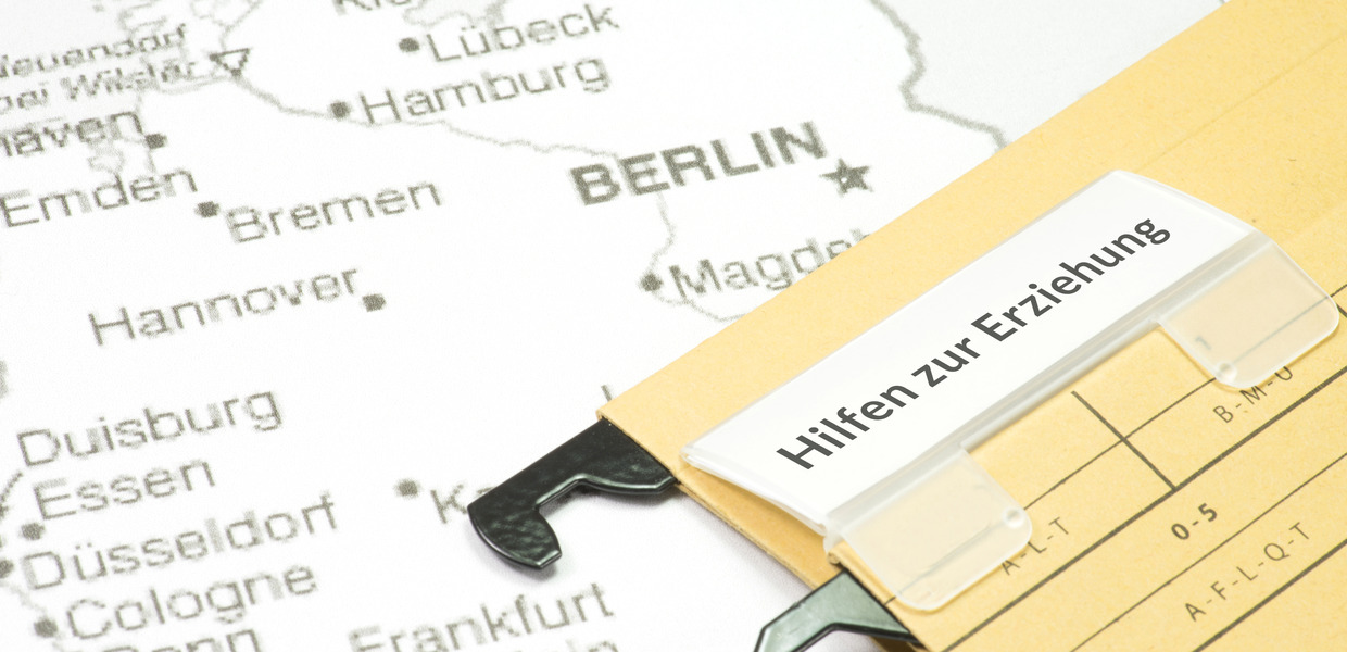 Aktenmappe mit dem Text Hilfen zur Erziehung liegt auf einer Landkarte