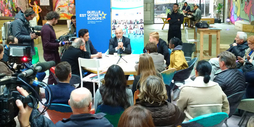 A bunch of citizens is sitting around a table, discussing.