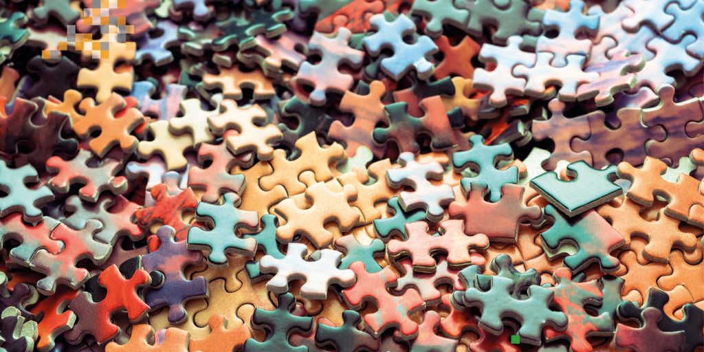 Many colorful puzzle pieces lie jumbled up on a table