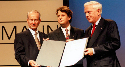 Reinhard Mohn übergibt den Carl Bertelsmann Preis 1997 an Lodewijk de Waal und Hans Blankert. Die drei Männer halten die Preis-Urkunde in die Kamera.