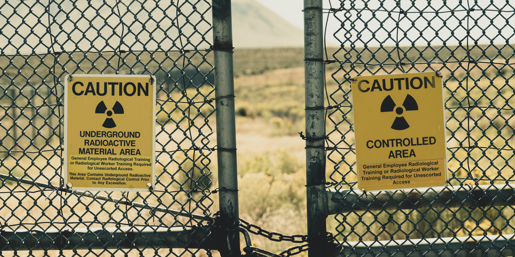 Slightly opened fence gates with two atomic signs