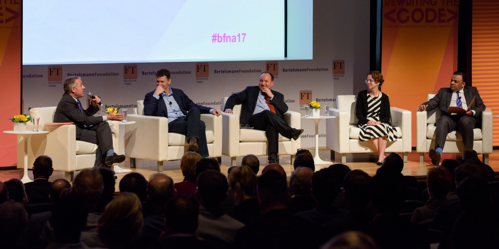 Teilnehmer einer Diskussionsrunde sitzen während der Jahreskonferenz der Bertelsmann Foundation in Sesseln auf einem Podium.