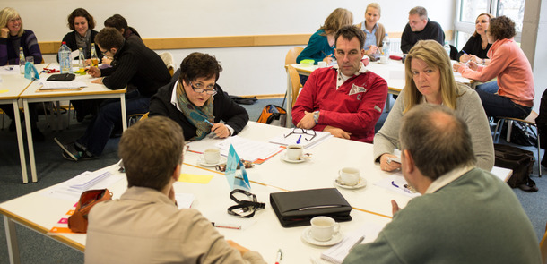 Lehrer sitzen in Gruppen an Tischen und diskutierenLehrer sitzen in Gruppen an Tischen und diskutieren