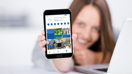 Eine Frau hält ein Handy hoch mit dem Profil des Kanals.