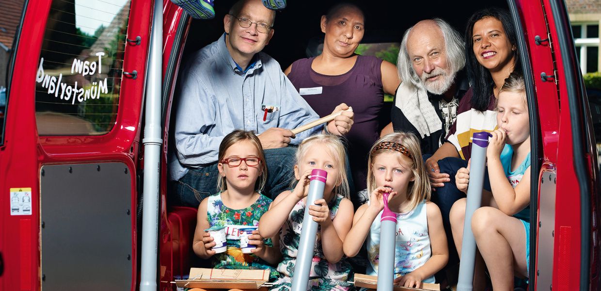 (© Arne Weychardt) Kinder mit selbst gebastelten Intsrumenten sitzen im roten Caddy der Mobilen Musikwerkstatt