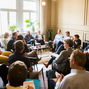 ca. 18 Teilnehmende am Workshop der Denkfabrik am 5.05.24 sitzen zusammen in einem Raum und diskutieren