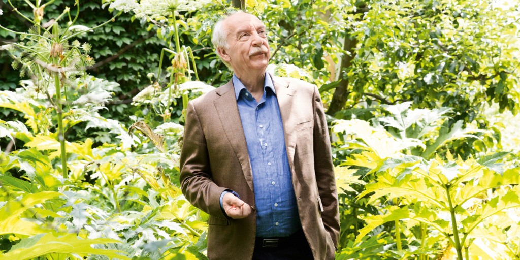 Der Berliner Psychologe Gerd Gigerenzer steht umringt von Bäumen und Grünpflanzen und blickt in die Ferne.