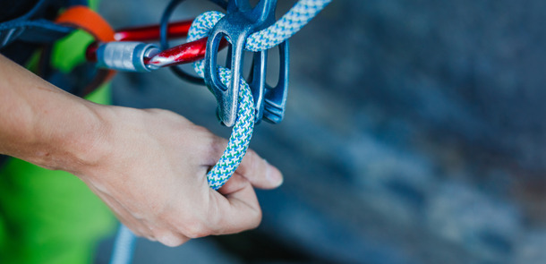 A climber wears safety equipment and holds the safety rope by hand.A climber wears safety equipment and holds the safety rope by hand.