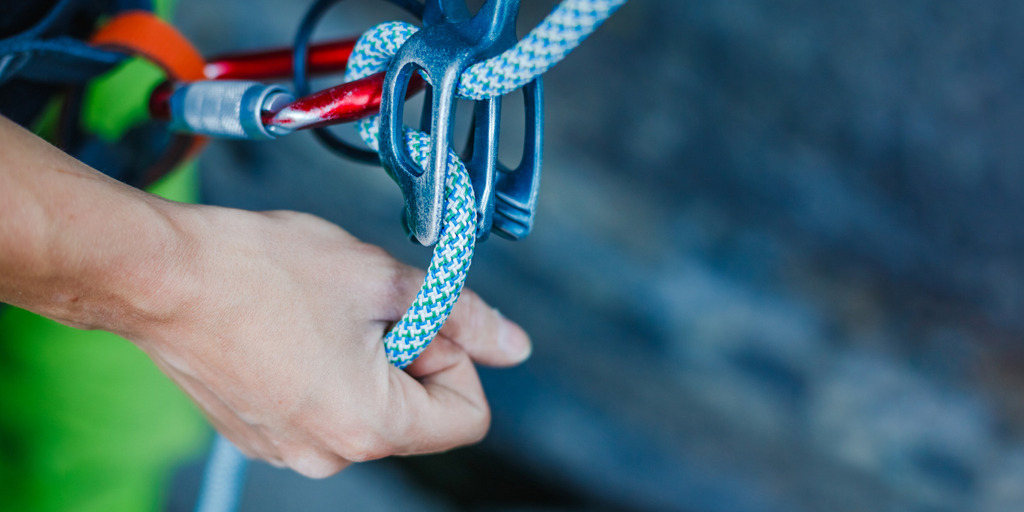 A climber wears safety equipment and holds the safety rope by hand.