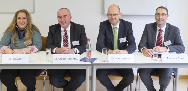 Vier Personen sitzen an einem TischVier Personen sitzen an einem TischVier Personen sitzen an einem Tisch