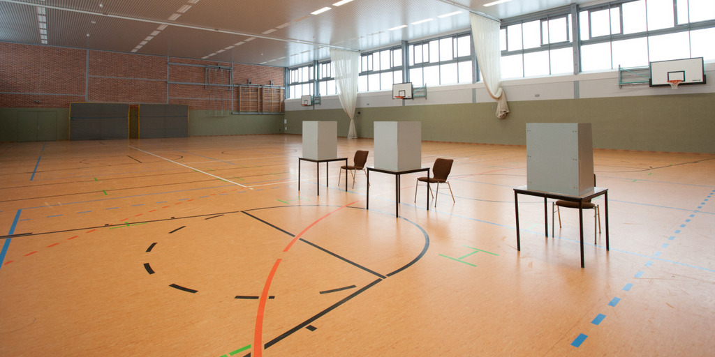 Drei leere Wahlkabinen in einer Turnhalle, die als Wahllokal genutzt wird.