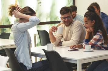 Eine Gruppe von Büroangestellten sitzt im Firmencafé und genießt die Kaffeepause und die Mittagspause.