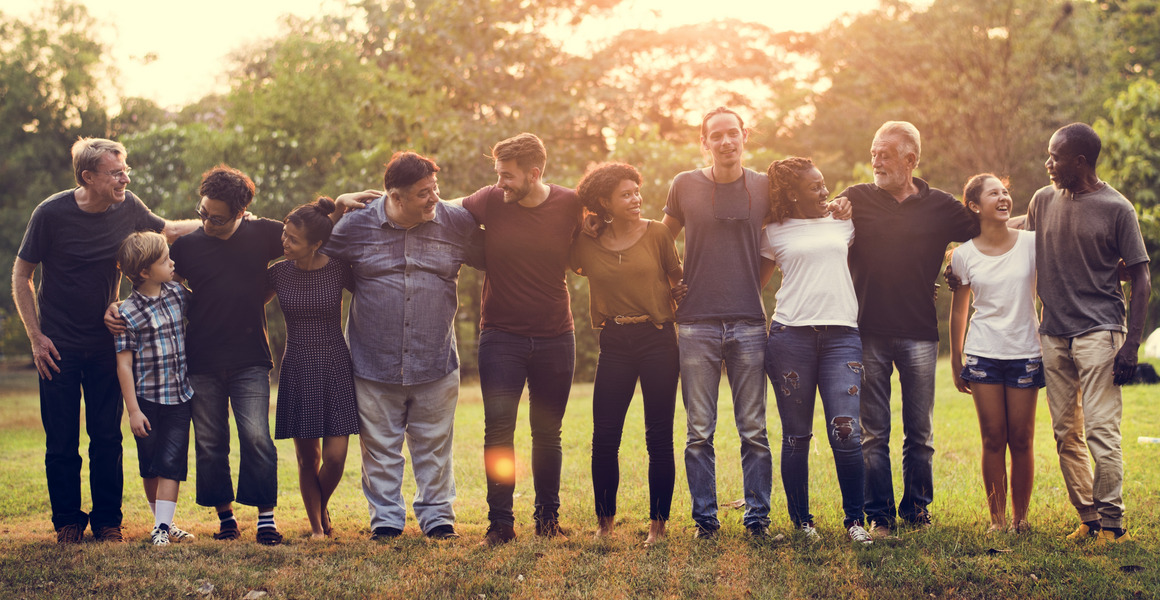 a bunch of young people in the green, standing arm in arm in a row. Sun sparcled