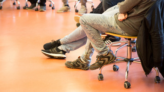 Personen sitzen in einem Stuhlkreis