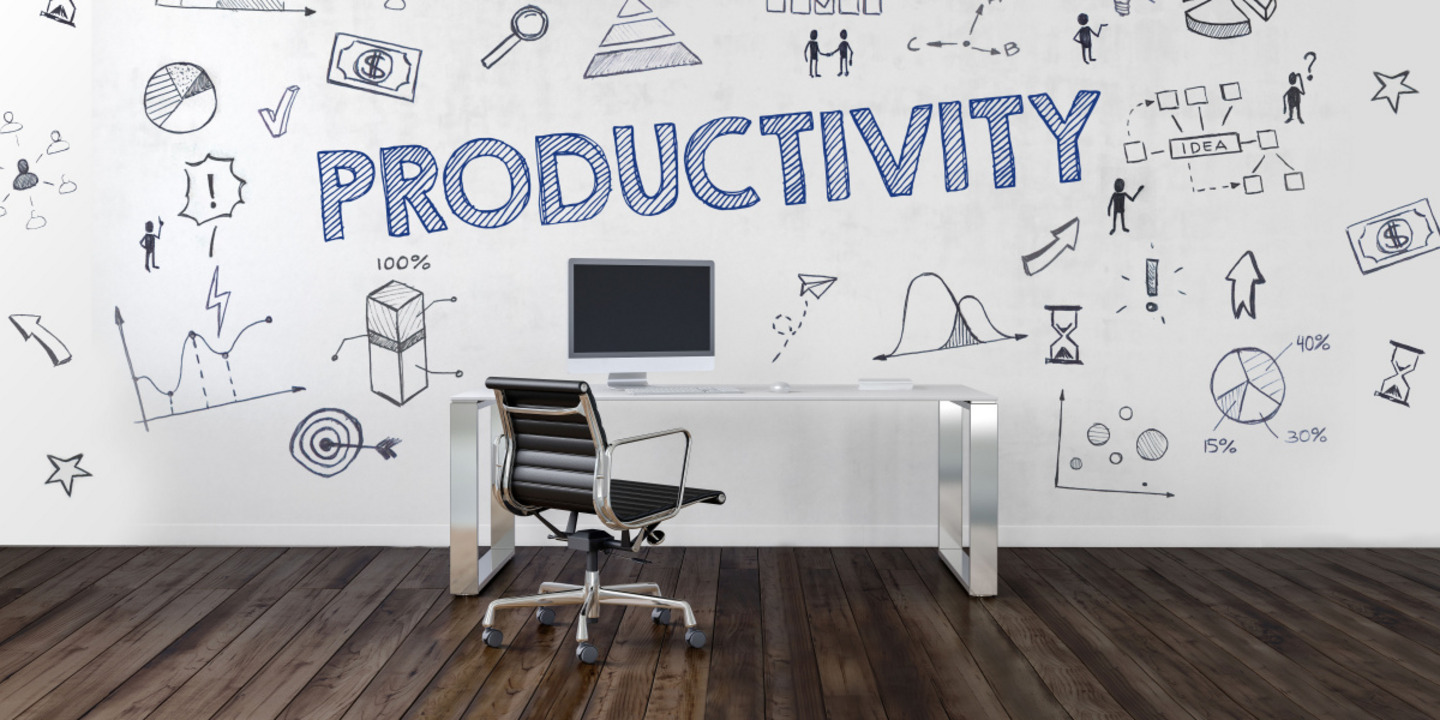 In a room, the word Productivity appears like a graphic. In front of the wall stands a brown office chair at a desk.