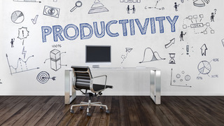 In einem Raum steht grafiitiartig das Wort Productivity. Vor der Wand steht ein brauner Bürostuhl an einem Schreibtisch