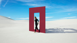 Frau geht im Sand durch eine Tür