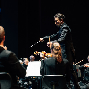 Cornelius Meister steht am Dirigentenpult und dirigiert das Orchester.