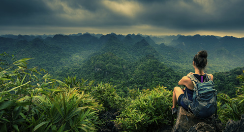 Blick von oben in den Dschungel einer Frau, die an der Bergkante sitzt