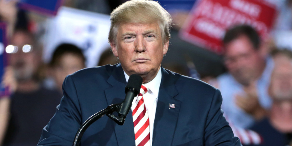 Donald Trump steht auf einer seiner Wahlkampfveranstaltungen am Rednerpult und zieht ein grimmiges Gesicht.