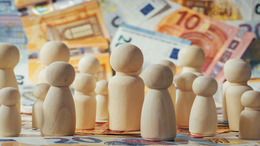 Spielfiguren aus Holz vor Euroscheinen