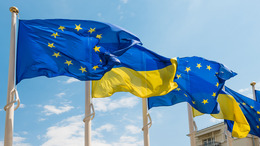 [Translate to English:] Die Flaggen der Ukraine und der Europäischen Union flattern im Wind am blauen Himmel