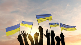 Silhouette von erhobenen Armen, die die ukrainische Flagge schwenken