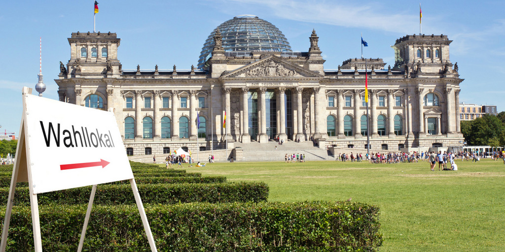 Vor dem Reichstagsgebäude in Berlin steht ein Schild, das die Richtung zu einem Wahllokal weist.