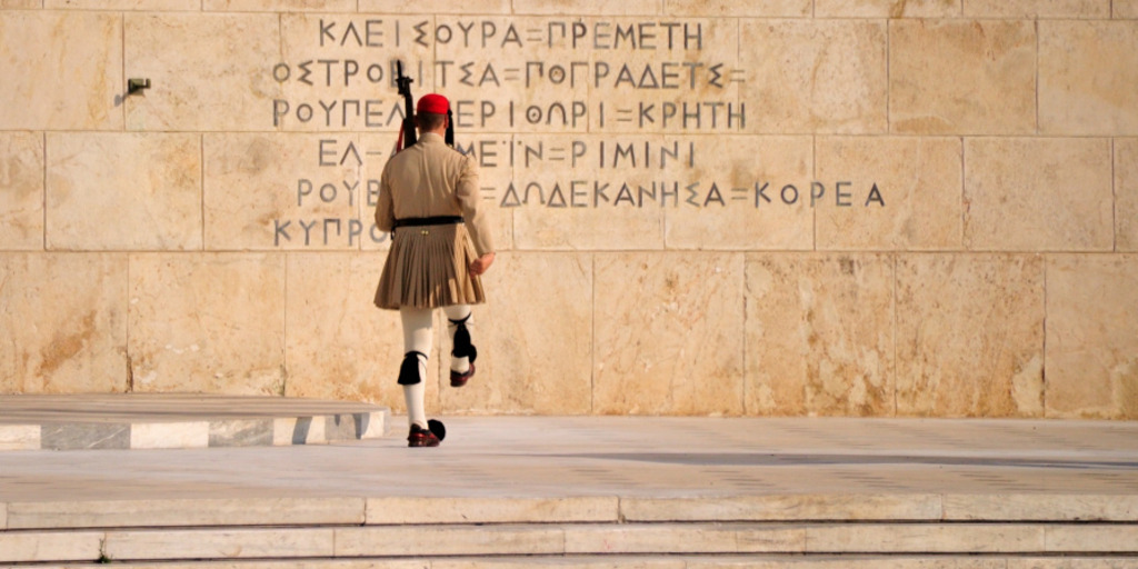 Ein Wachsoldat in traditioneller griechischer Tracht, ein Efzone, marschiert beim Wachwechsel vor dem griechischen Parlament in Athen auf eine Mauer zu.