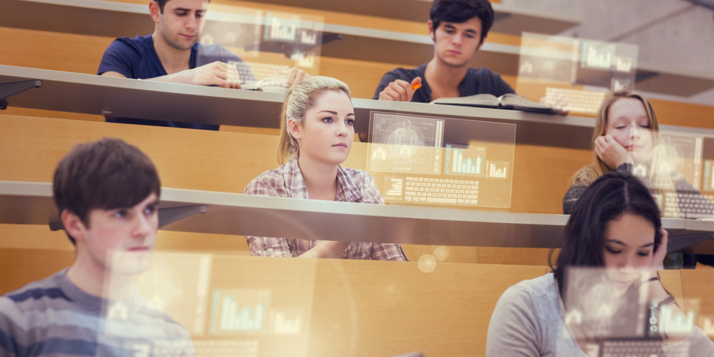Mehrere Studierende sitzen in einem Hörsaal vor den Projektionen virtueller Computerbildschirme. Zwei Studierende lesen in Büchern, eine Studierende hat die Augen geschlossen.