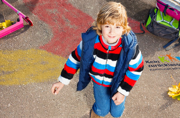 Ein Kind steht auf einer mit Kreide bemalten Fläche.