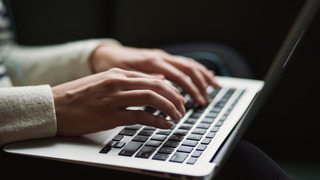 Eine Person tippt mit beiden Händen auf die Tastatur eines Laptops