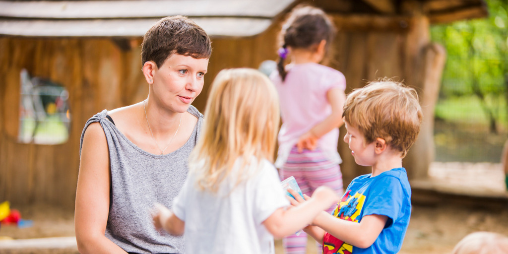 Eine junge Frau mit zwei Kindern auf dem Spielplatz