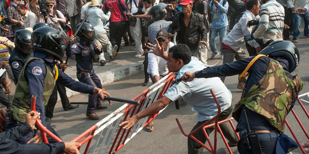 Bei Protesten in der kambodschanischen Hauptstadt Phnom Penh gerät ein Demonstrant zwischen Barrikaden und mehrere Polizisten, die mit dem Schlagstock auf ihn einschlagen.