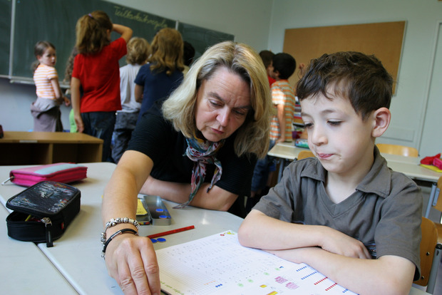 Im Klassenraum: Eine Lehrerin erklärt einem Schüler etwas im Einzelgespräch.