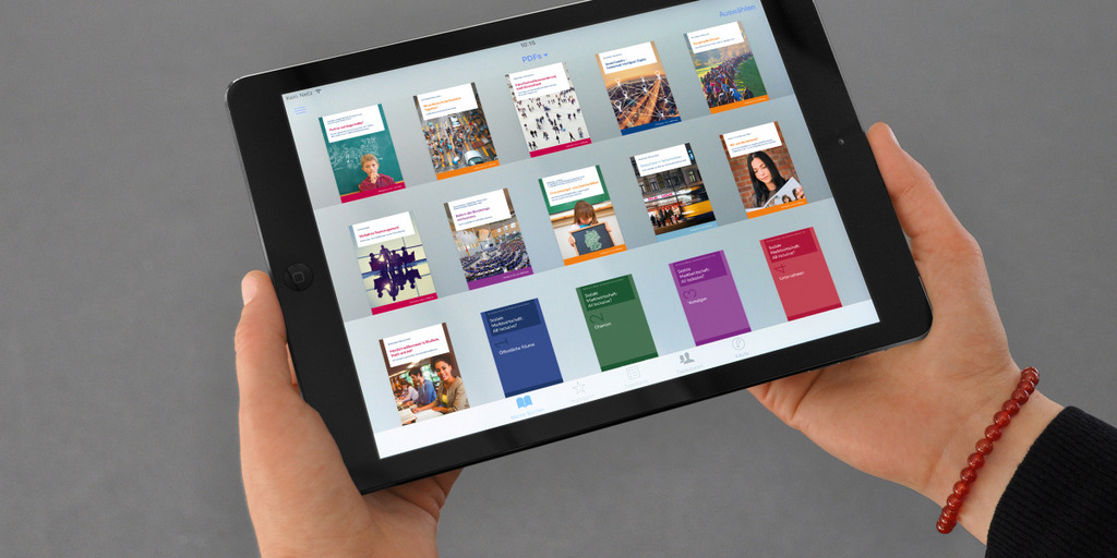 Eine Frau hält ein Tablet in ihren Händen, auf dem die Titel mehrerer Bücher aus dem Verlag Bertelsmann Stiftung zu sehen sind.